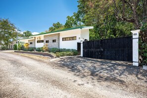 A modern two-story house with a gravel driveway and a black gate. - Pool & Large Patio: Playa Carrillo 3BR Family Home (Playa Carrillo)