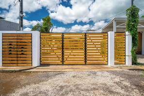 A gated entrance with a wooden fence and a white wall. - Private 2-Studio Retreat Near Playa Del Coco! (Playas del Coco)