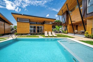 A modern hotel with a swimming pool, wooden exterior, and a covered outdoor seating area. - Private 2-Studio Retreat Near Playa Del Coco! (Playas del Coco)