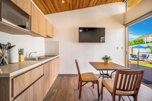 A modern kitchen with wooden cabinets, a stainless steel sink, and a flat-screen TV mounted on the wall. - Private 2-Studio Retreat Near Playa Del Coco! (Playas del Coco)