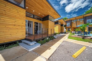 A modern building with wooden exterior walls, large windows, and a patio area with outdoor seating. - Private 2-Studio Retreat Near Playa Del Coco! (Playas del Coco)