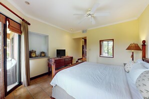 A hotel room with a bed, a television, a desk with a computer, and a window with curtains. - Playa Conchal Resort Condo w/ Ocean View (Playa Conchal)