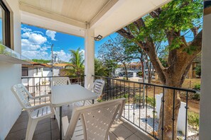 A covered outdoor seating area with a table and chairs, a railing, and a view of the surrounding neighborhood. - Playas del Coco Condo w/ Pool: Walk to Beach! (Playas del Coco)