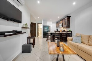 A modern kitchen with dark cabinets, a dining area with a wooden table, and a living room with a beige sofa. - 4 Mi to Beach! Playa Grande Apartment (Playa Grande)