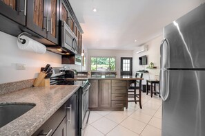 A modern kitchen with granite countertops, stainless steel appliances, and wooden cabinetry. - 4 Mi to Beach! Playa Grande Apartment (Playa Grande)