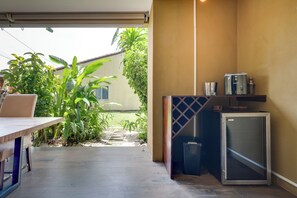 Eine kleine Küche mit Kühlschrank, einer Arbeitsplatte und einem Fenster mit Blick auf einen Garten.