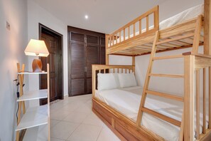 Ein Zimmer mit einem Etagenbett, einem Schreibtisch mit Lampe und einem Kleiderschrank.