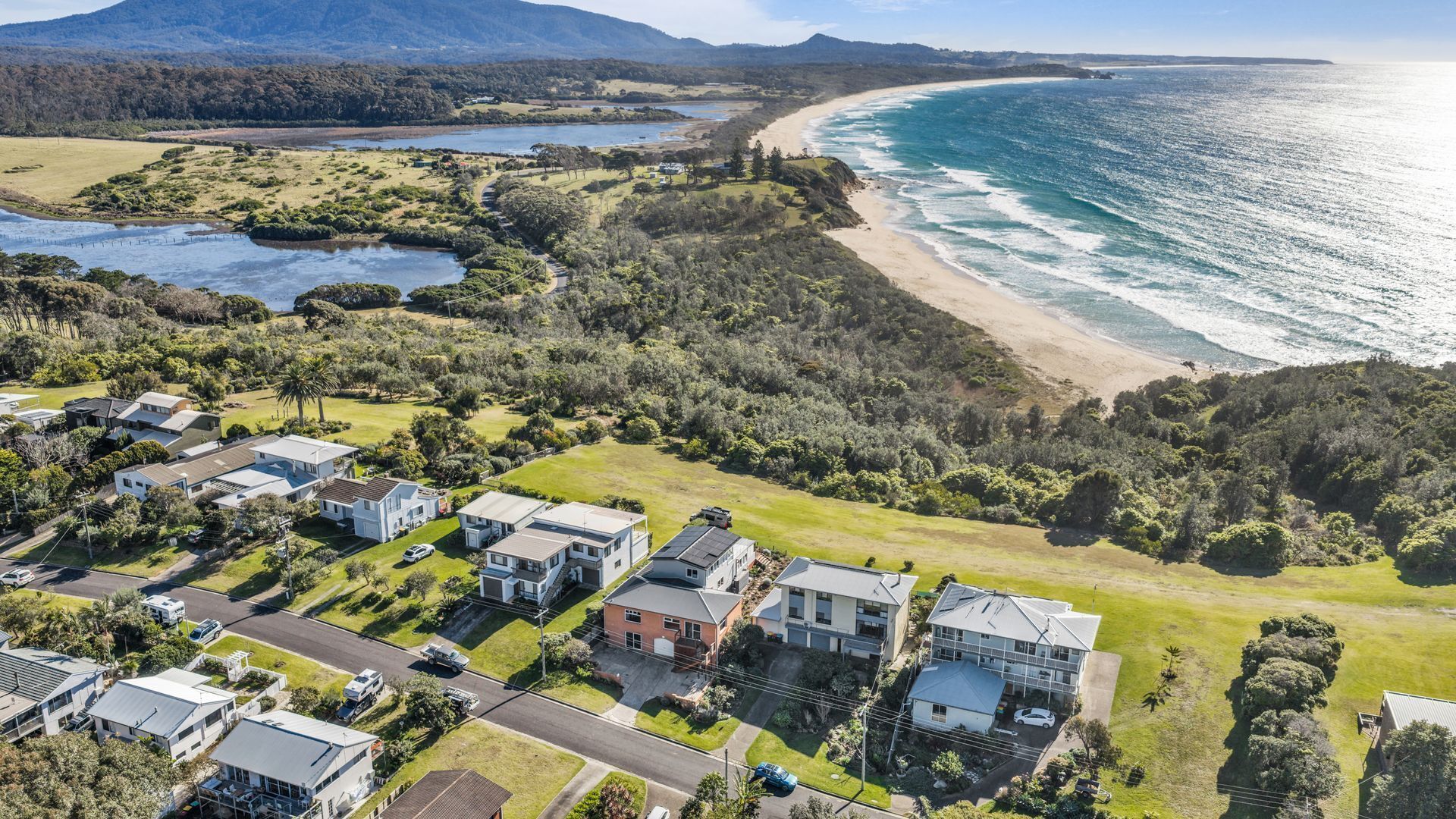 A coastal residential area with houses, a beach, and a river.
