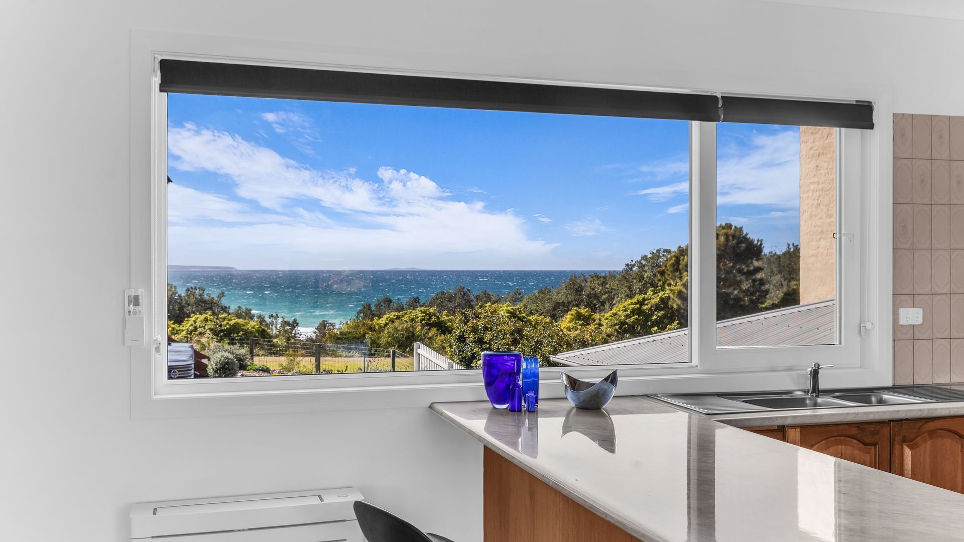 A kitchen with a large window overlooking a coastal landscape.