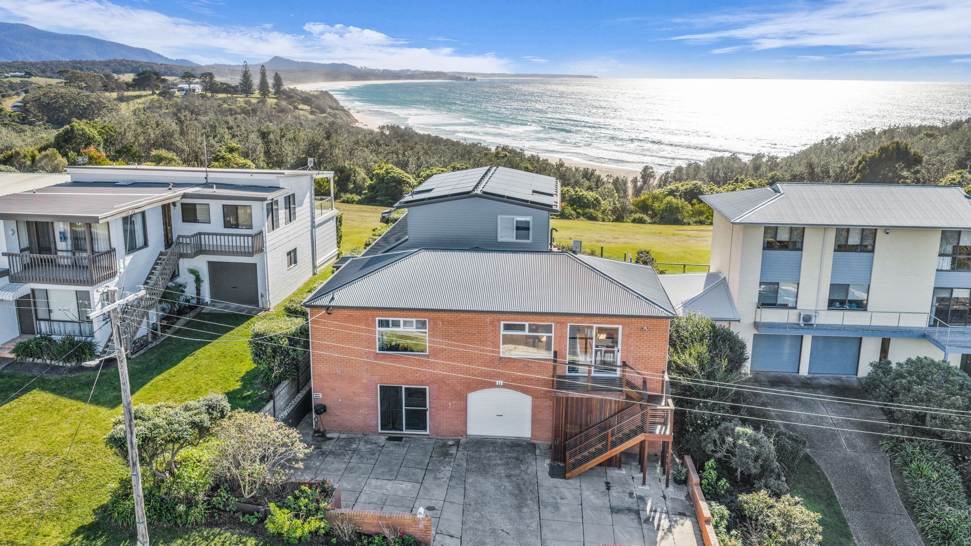 A residential area with houses, a view of the ocean, and a hilly landscape.