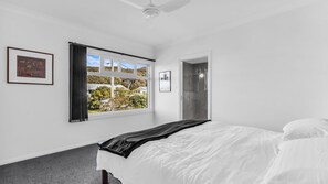 Ein Schlafzimmer mit einem Bett, einem Fenster mit Vorhängen und einer Tür.