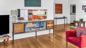Ein modernes Wohnzimmer mit einem roten Sofa, einem Glastisch und einer Holzeinrichtung mit Büchern.