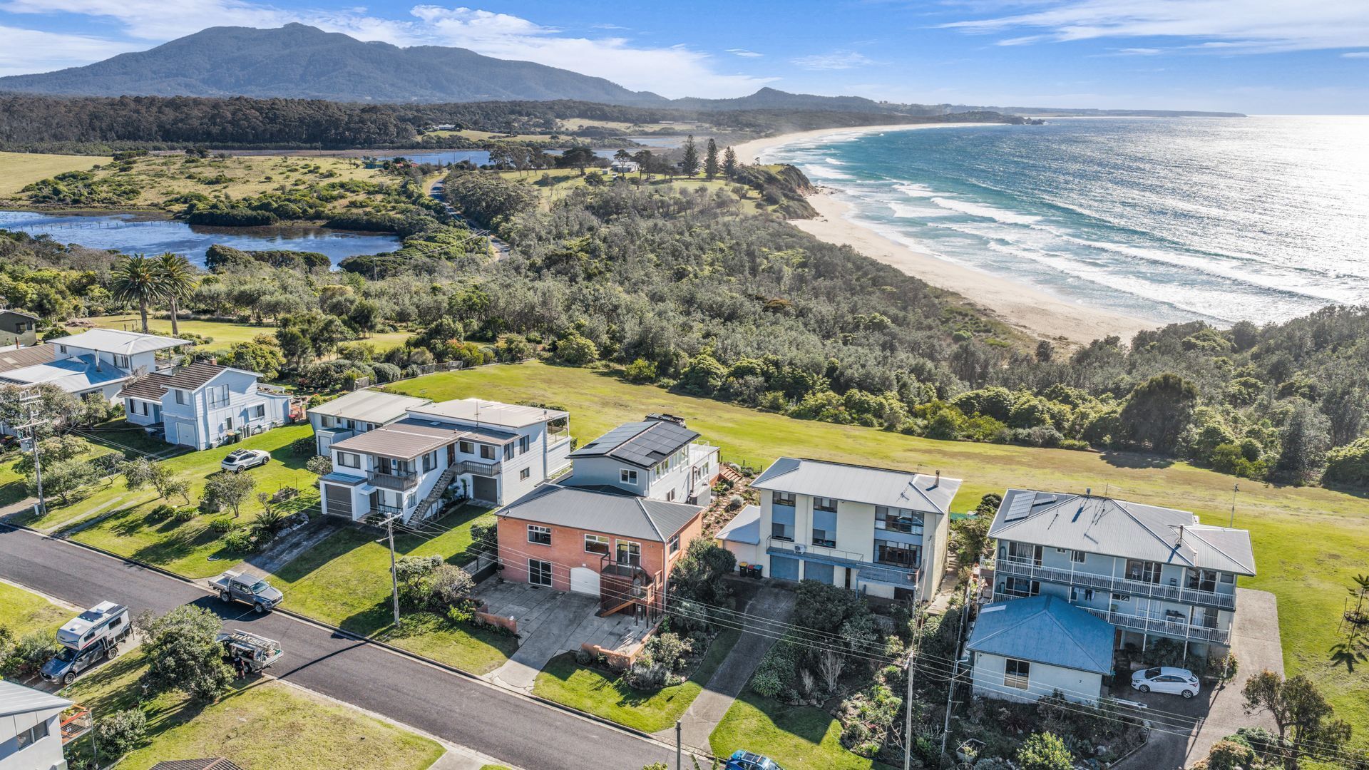 A residential area with houses, a road, and a beach.