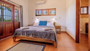 Quarto com cama, mesa de cabeceira, janela e ar condicionado.