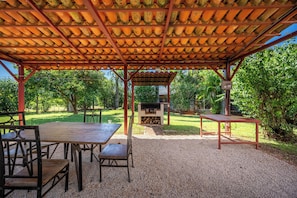 An outdoor covered patio area with a grill, tables, and chairs. - Santa Cruz Group Getaway w/ Pool: Walk to Beach (Junquillal)