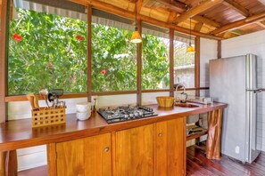 Una cocina con mostrador de madera, estufa a gas, lavamanos y refrigerador.