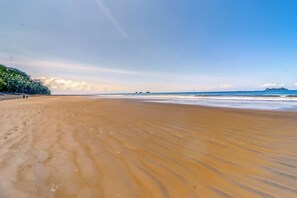 Una playa extensa de arena con olas suaves y cielo despejado.