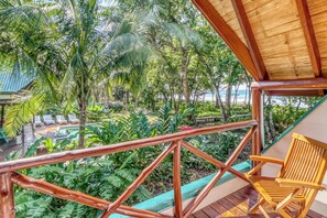 Terraza de madera con vista a un jardín exuberante y una piscina.