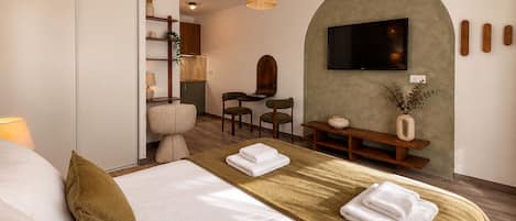 Una habitación de hotel con una cama, un escritorio, un televisor y una zona de estar.