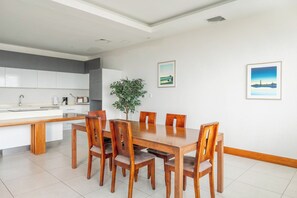 A modern kitchen with white cabinets, a dining table with six chairs, and a potted plant. - El Roble Penthouse: Wraparound Deck, Views (El Roble)