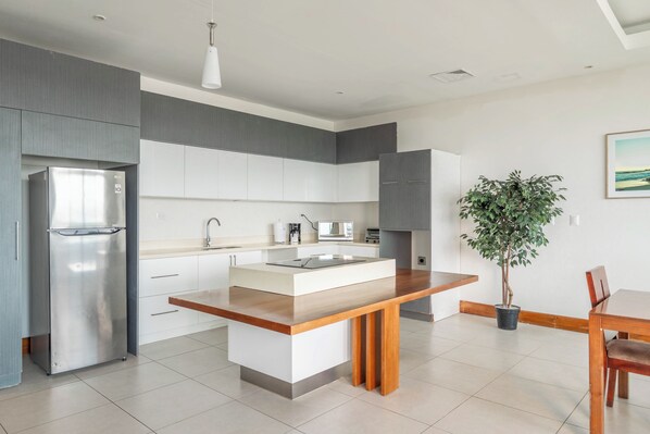 A modern kitchen with a built-in island, stainless steel appliances, and a dining area with a wooden table and chairs.
