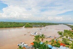 A coastal area with boats docked along the shore, surrounded by greenery and a clear sky.