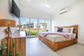 A bedroom with a large bed, a desk, a chair, a television, and a ceiling fan. - Playa Avellanas Villa: Modern Luxury, Pool, Views (Playa Avellanas)