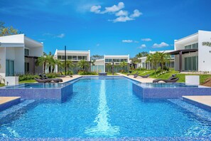 A modern resort with a central swimming pool, lounge chairs, and contemporary architecture. - Playa Avellanas Villa: Modern Luxury, Pool, Views (Playa Avellanas)
