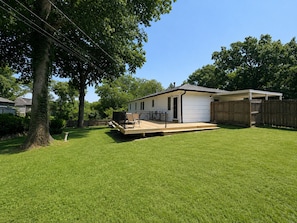 A single-story house with a deck, a fenced yard, and a large tree. - The KC Garden Retreat- 10 Mins to Everything! (Kansas City)