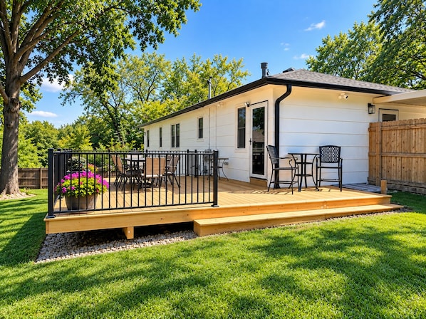 A single-story house with a deck, a patio with outdoor furniture, and a fenced yard.