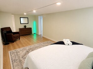 A hotel room with a bed, a chair, a dresser, a mirror, and a green light.