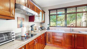 A kitchen with wooden cabinets, a built-in oven, a sink, and a window with a view of greenery.