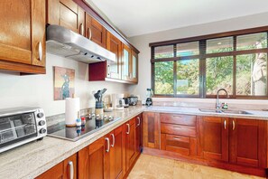 A kitchen with wooden cabinets, a built-in oven, a sink, and a window with a view of greenery.