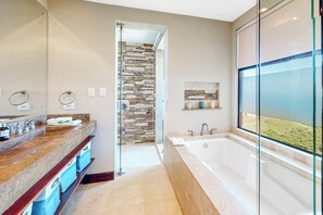 A modern bathroom with a large bathtub, a glass shower enclosure, and a vanity with a marble countertop. - Ocotal Hilltop Condo: Ocean Views, Pool Access (Playa Ocotal)