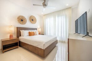 A modern bedroom with a bed, nightstands, a ceiling fan, and a TV. - Ocean-View Tamarindo: Community Pool Access (Tamarindo)
