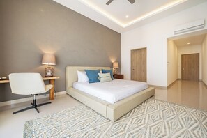 Une chambre à coucher moderne avec un grand lit, des lampes de chevet, un fauteuil et un tapis.