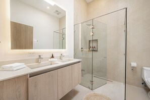 A modern bathroom with a glass-enclosed shower, a large mirror, and a vanity with a sink and countertop. - Ocean-View Tamarindo: Community Pool Access (Tamarindo)