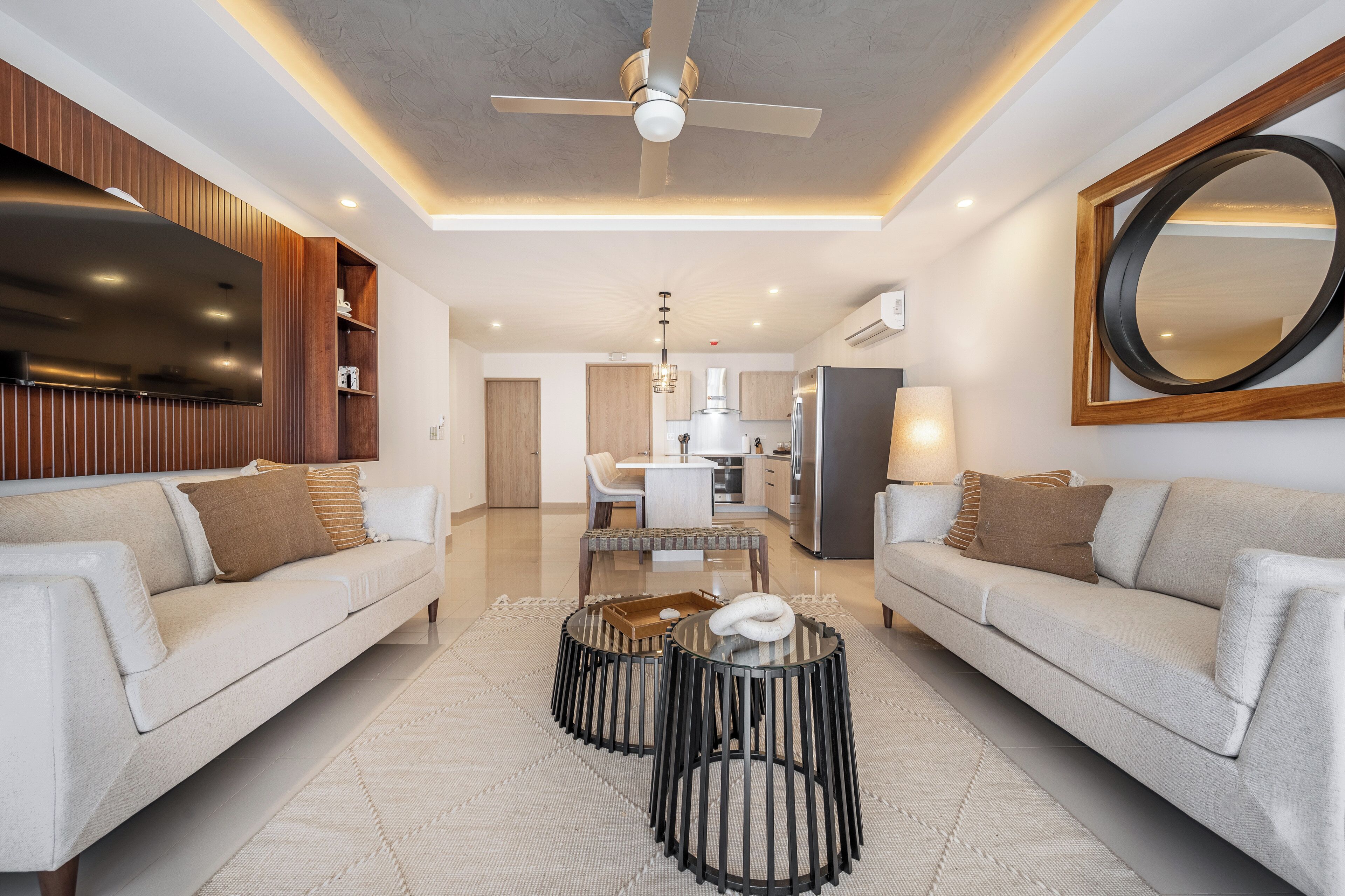 A modern living room with a sofa, coffee table, and a dining area.