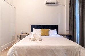 Ein Hotelzimmer mit Bett, Nachttisch, Vorhängen und einer Klimaanlage.