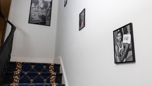 Una escala amb un fermall blau estampat i una barana, que condueix a un sortidor amb tres fotografies emmarcades a la paret.