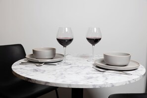 A round marble table with two white bowls and two wine glasses on it. - Spruce Villa - 1st Floor Grand King 1BR (Philadelphia)