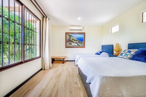 Hotellihuone, jossa on suuri ikkuna, taulu, penkki ja sängyssä tyynyjä.