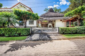 A house with a thatched roof, a paved entrance, and a well-maintained garden.