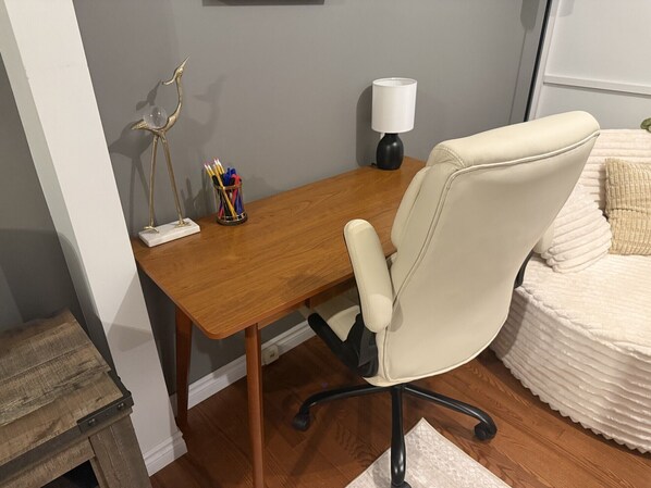 A wooden desk with a white chair, a lamp, and a pen holder with pencils.