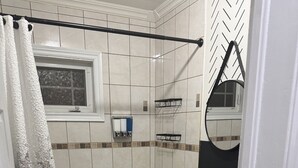 A bathroom with a bathtub, a white sink, a mirror, and a toilet. - Grand Falls-Windsor Gem | King Bed + Movie Room (Grand Falls-Windsor)