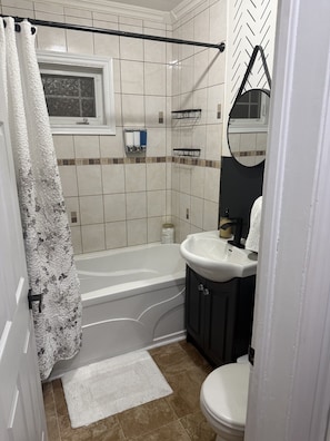 Un bagno con una vasca, un lavandino bianco, uno specchio e un water.