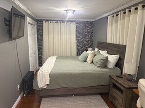 Una camera da letto con un letto, un comodino, una lampada e un televisore appeso al muro.