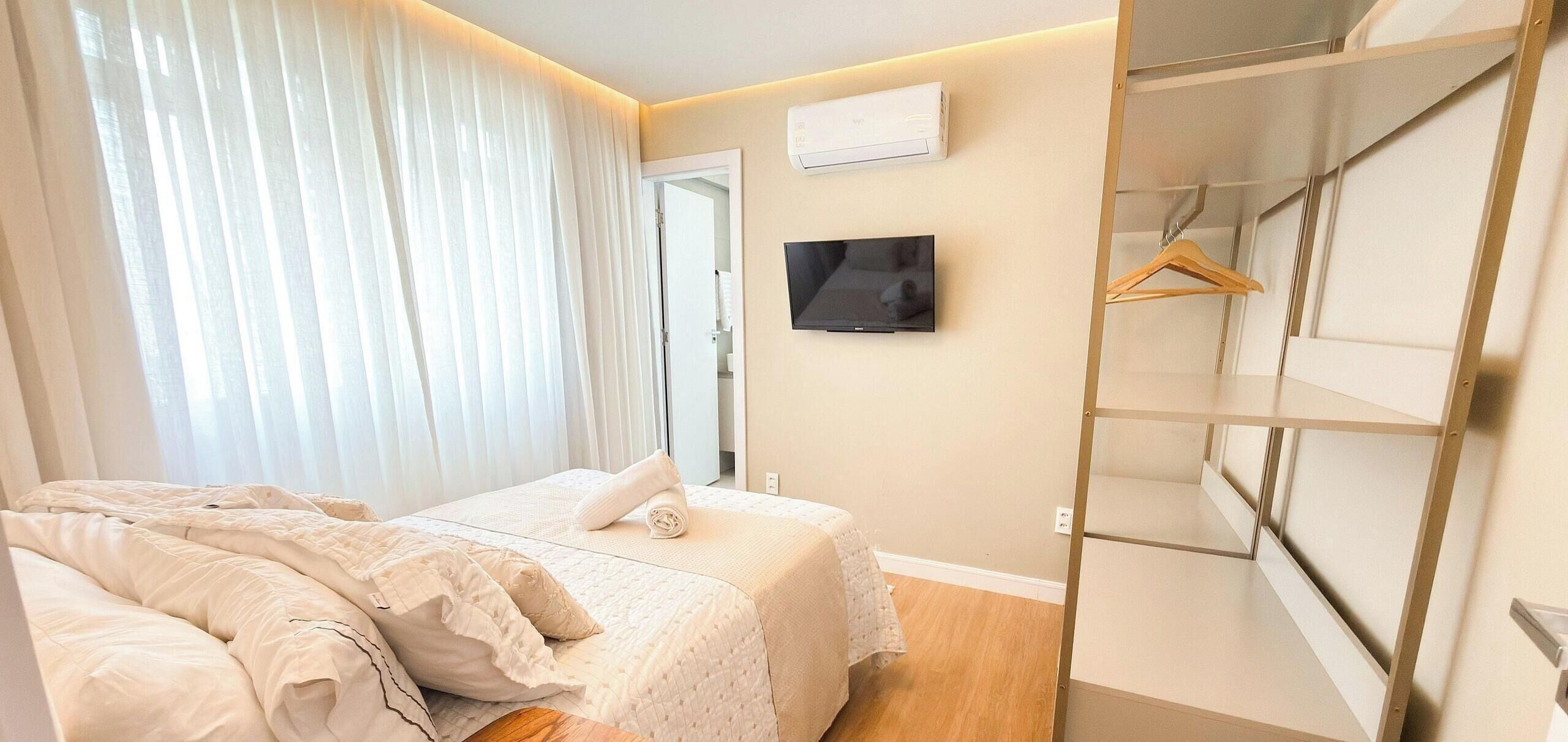 Un dormitorio con cama, televisión, equipo de aire acondicionado y armario.