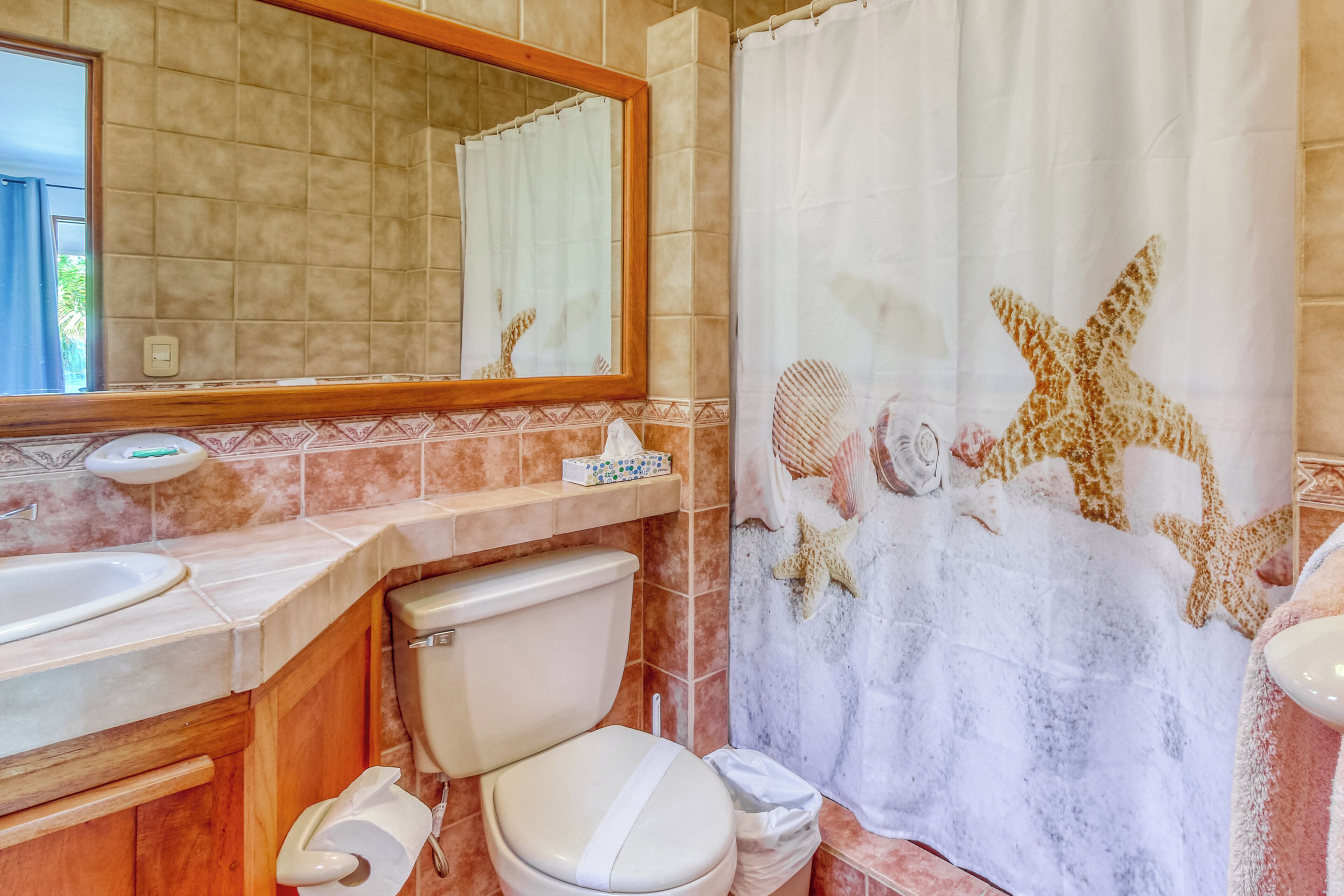 Un baño con inodoro, lavamanos y espejo.