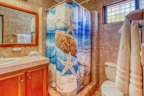 A bathroom with a shower curtain depicting a beach scene, a toilet, and a sink with a mirror above it. - 2-Unit Bundle: Bahia Pez Vela Resort Villas (Playa Ocotal)